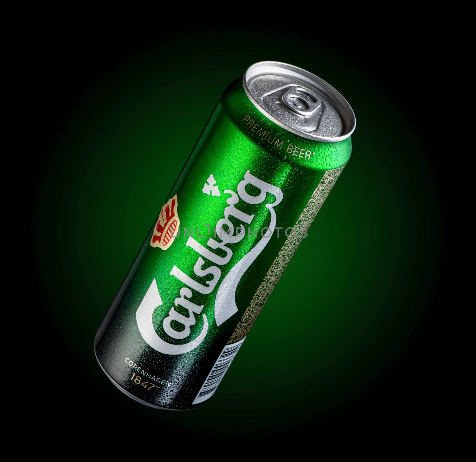 Almaty, Kazakhstan - October 11, 2019: can of beer Carlsberg with drops of water in a green background with illumination. Advertising a brand of beer
