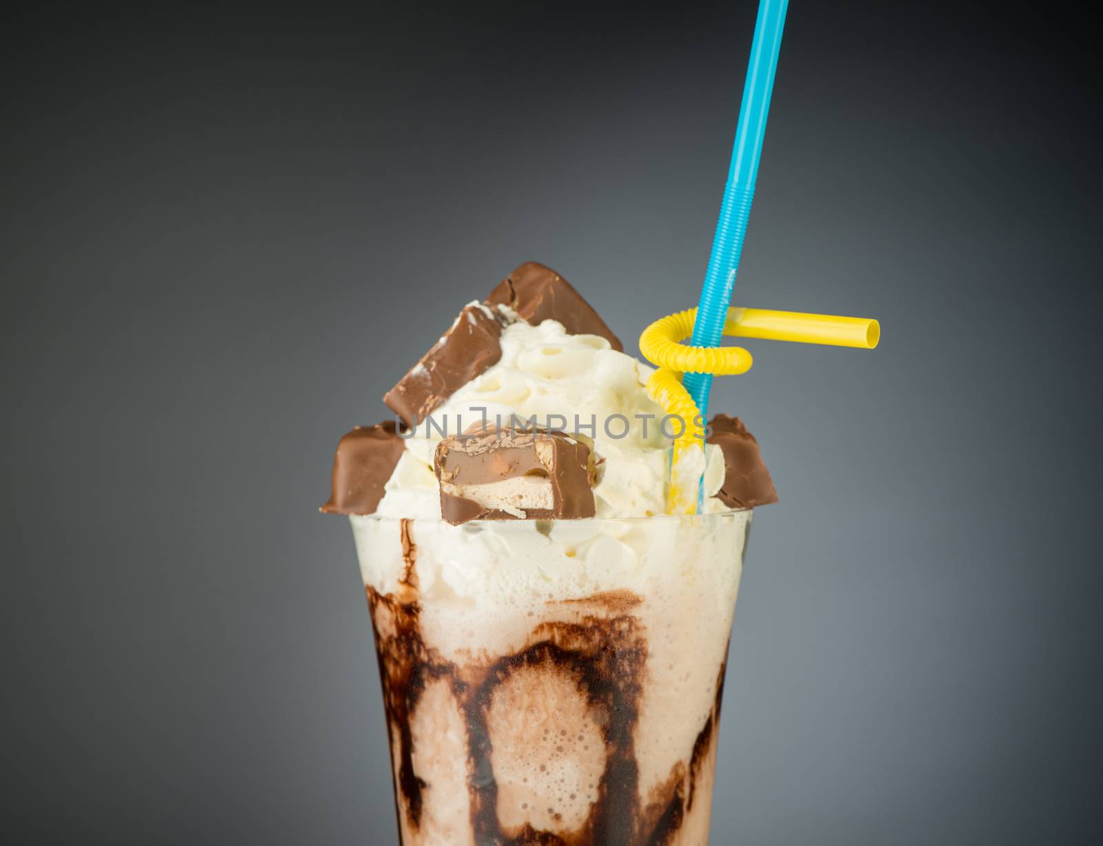 chocolate fruit cocktail ice cream with straw on grey backlit background, isolated. summer tropical smoothie