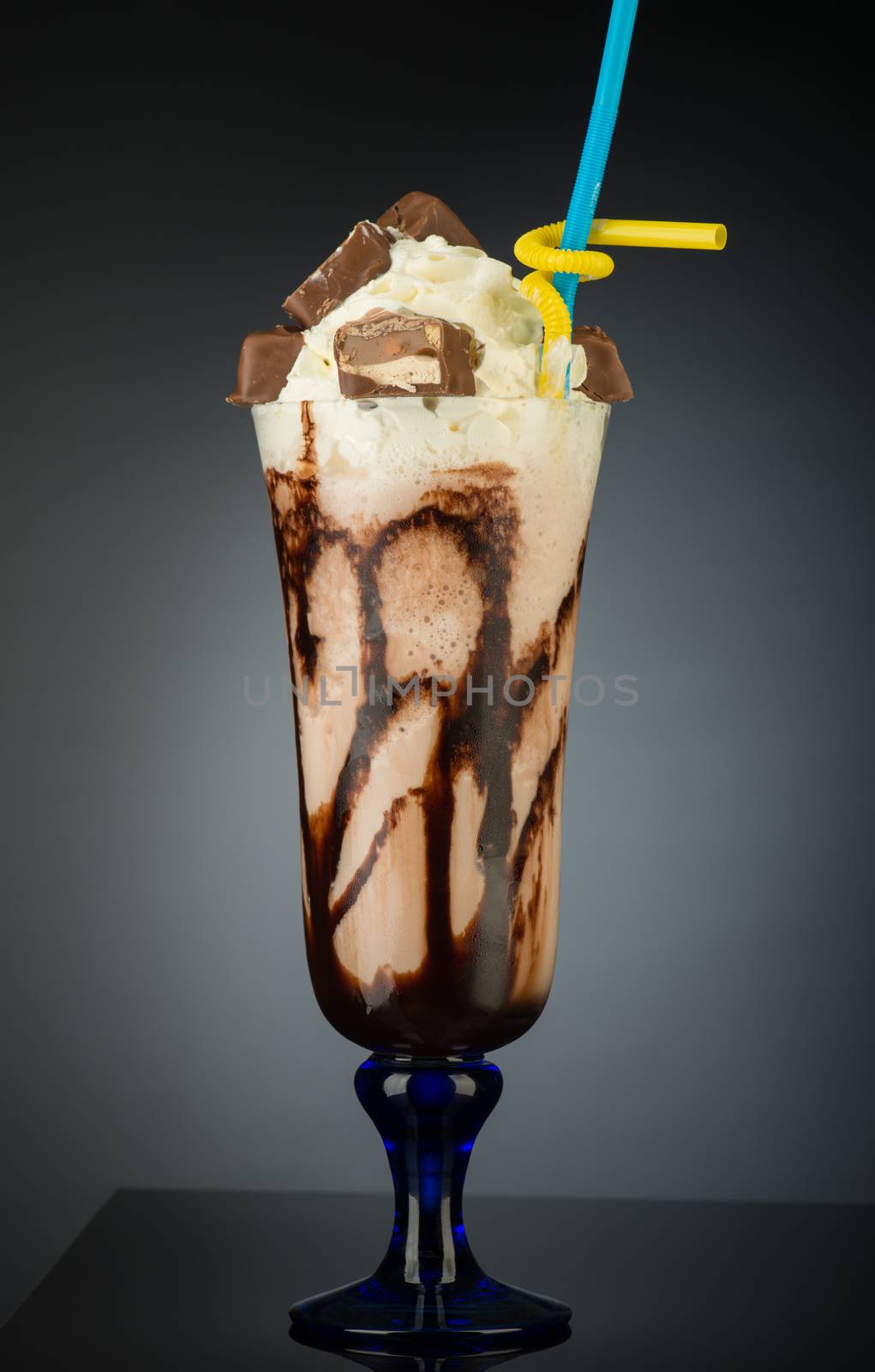 chocolate fruit cocktail ice cream with straw on grey backlit background, isolated. summer tropical smoothie