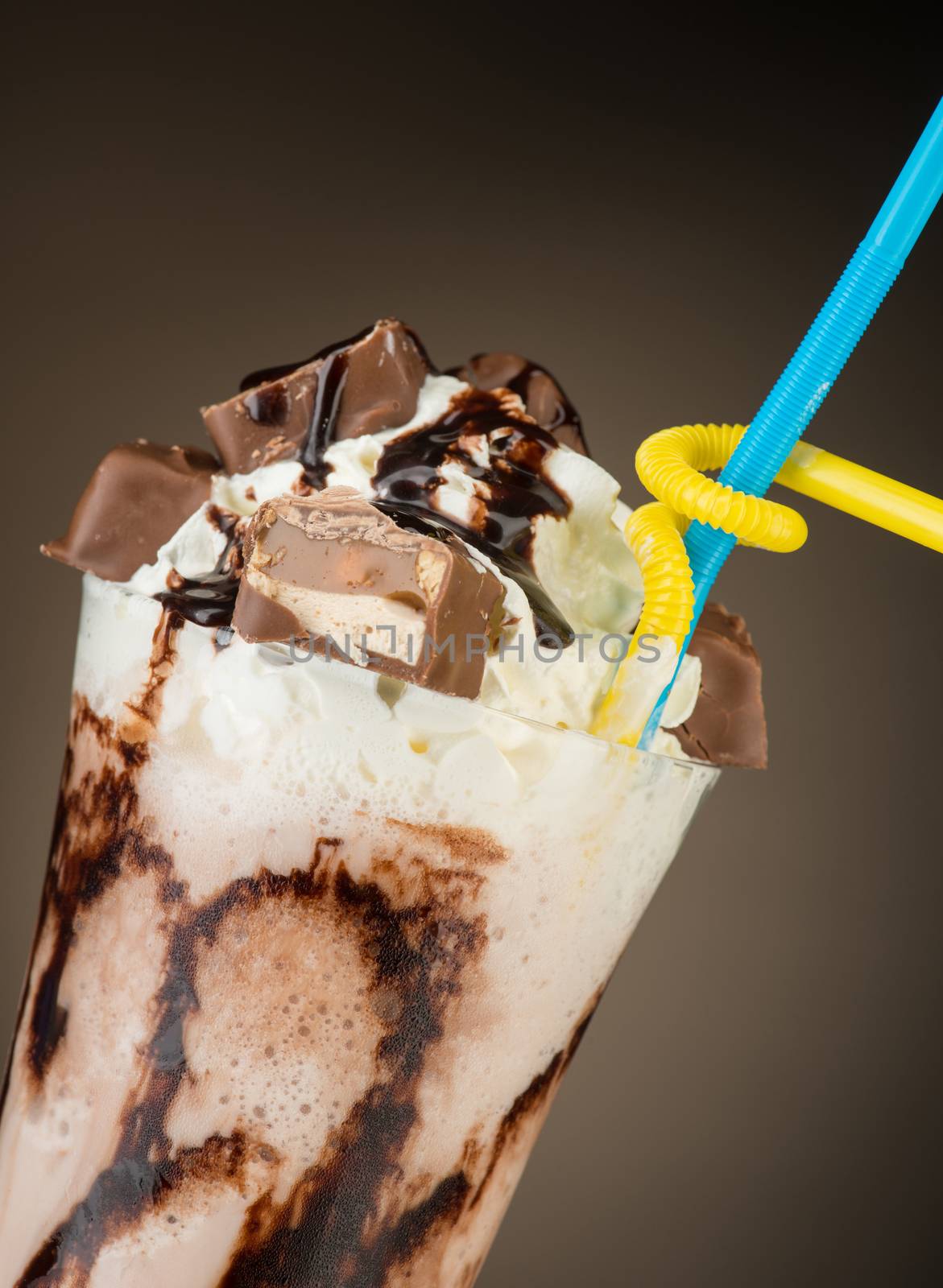 chocolate fruit cocktail ice cream with straw on brown backlit background, isolated. summer tropical smoothie