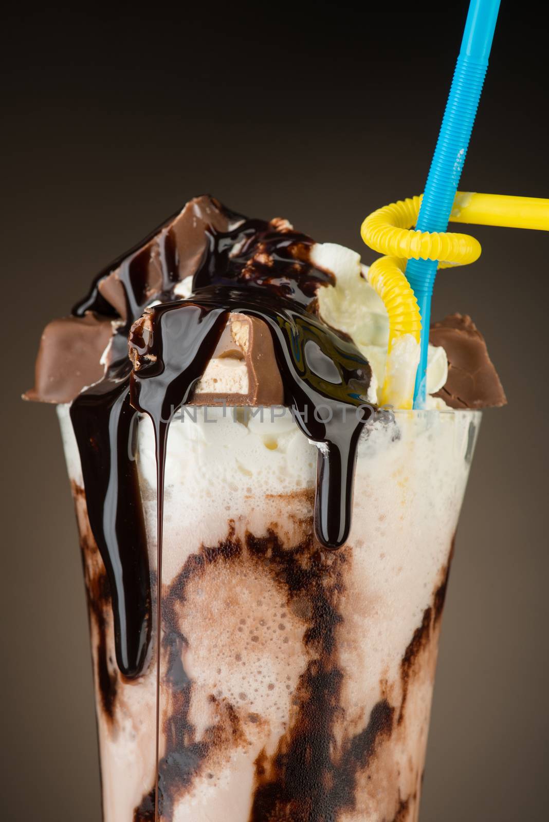 chocolate fruit cocktail ice cream with straw on brown backlit background, isolated. summer tropical smoothie