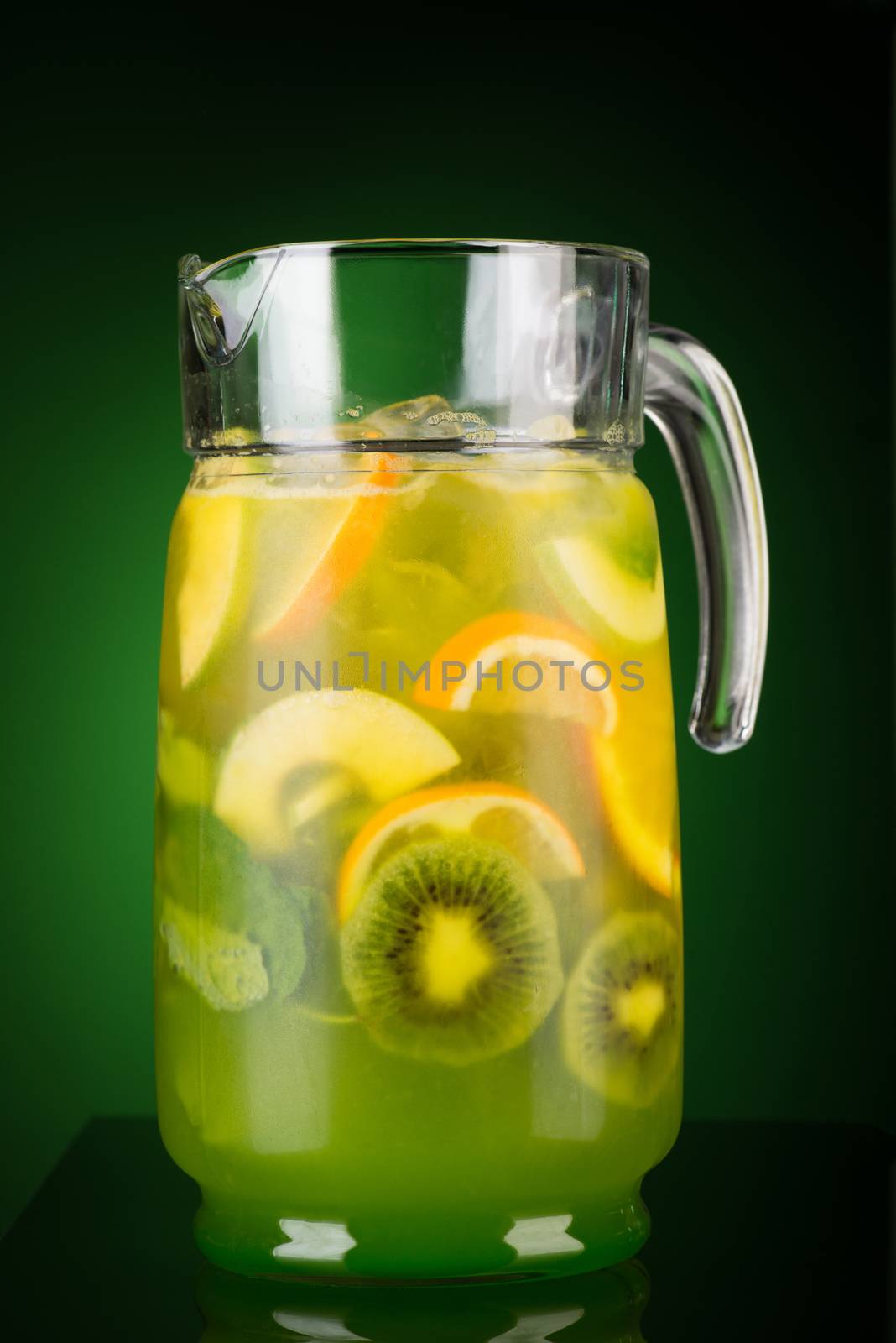 cold drink of citrus in a decanter on a green background. summer tropical juice