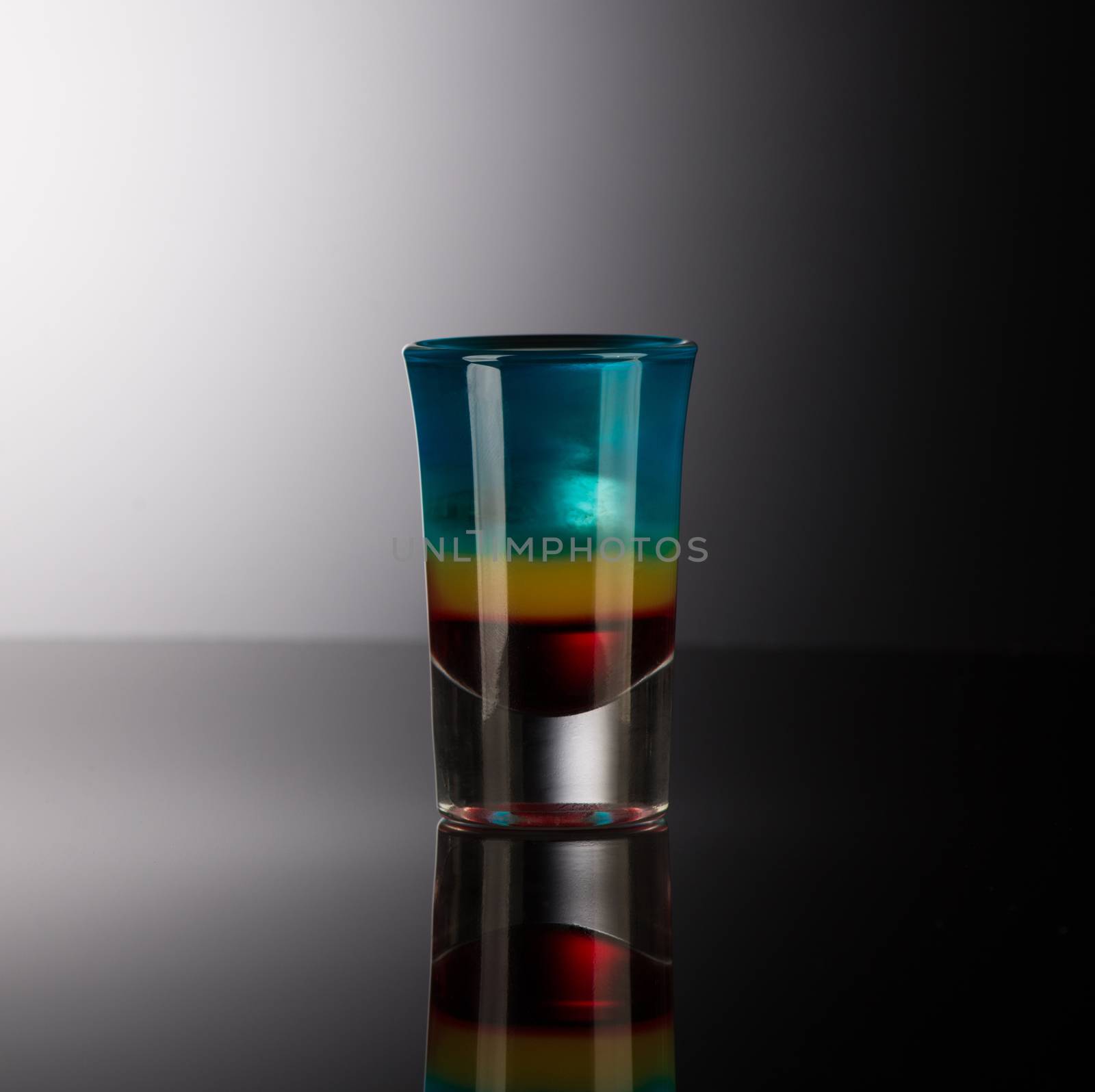 mixed alcoholic liquor in a shot glass isolated on a dark background with backlighting