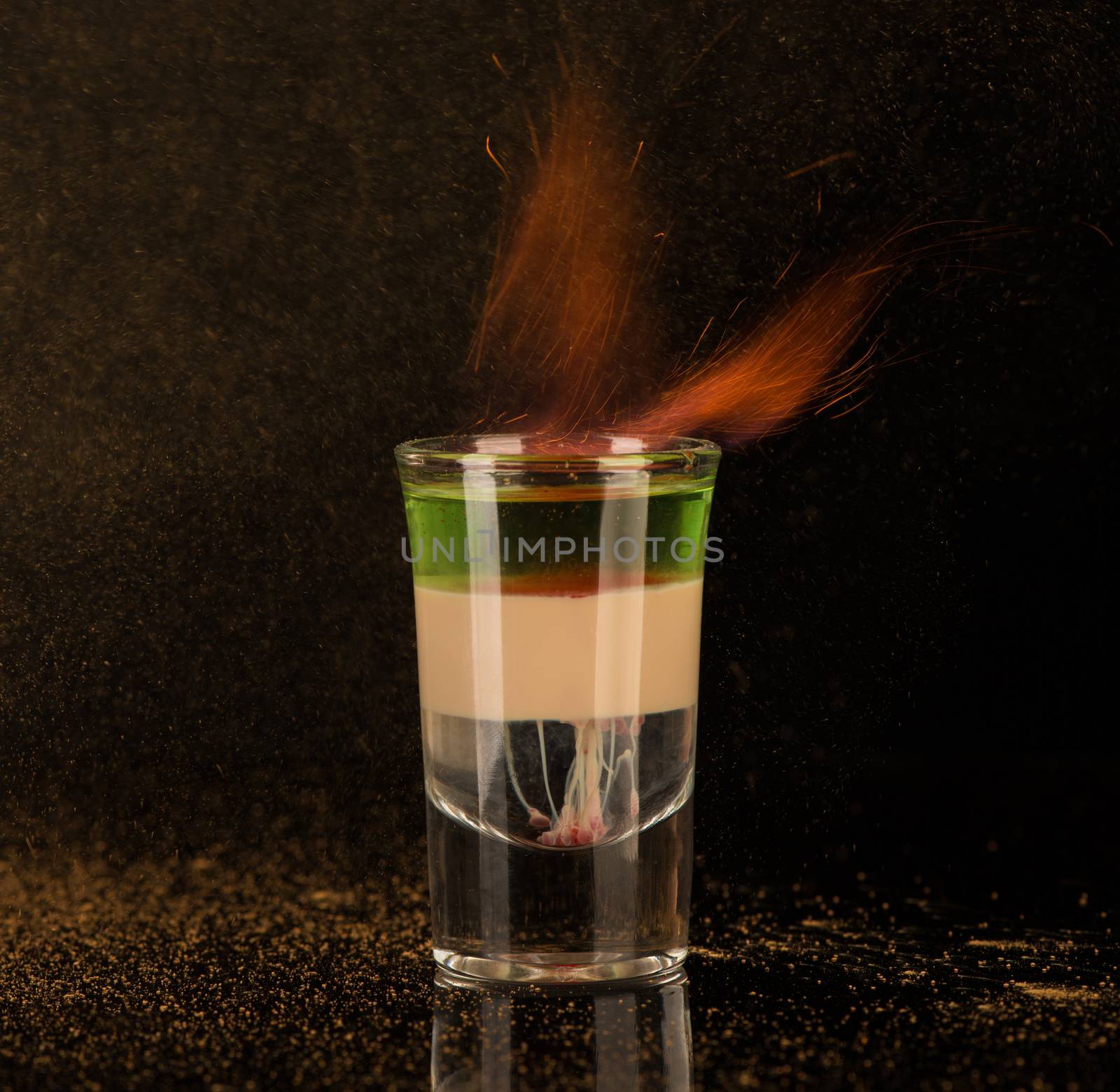 flaming cocktail with cinnamon in a shot glass on a black background, isolated