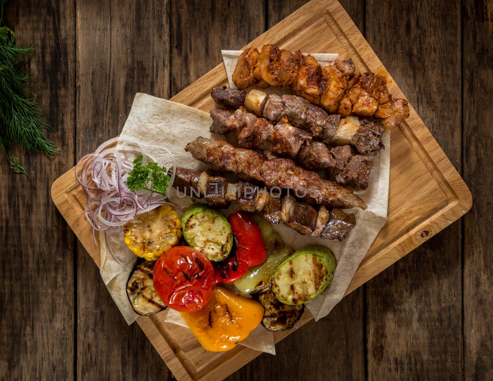 juicy pieces of grilled meat with vegetables on the kitchen board, top view