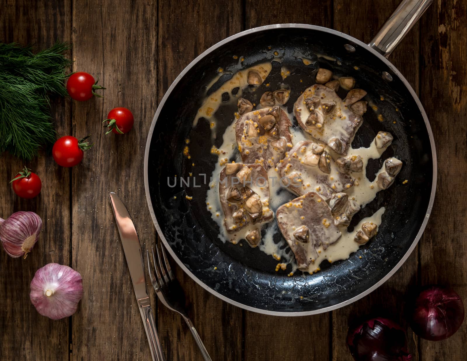 fried the meat and mushrooms seasoned with gravy in the pan on wooden background, top view