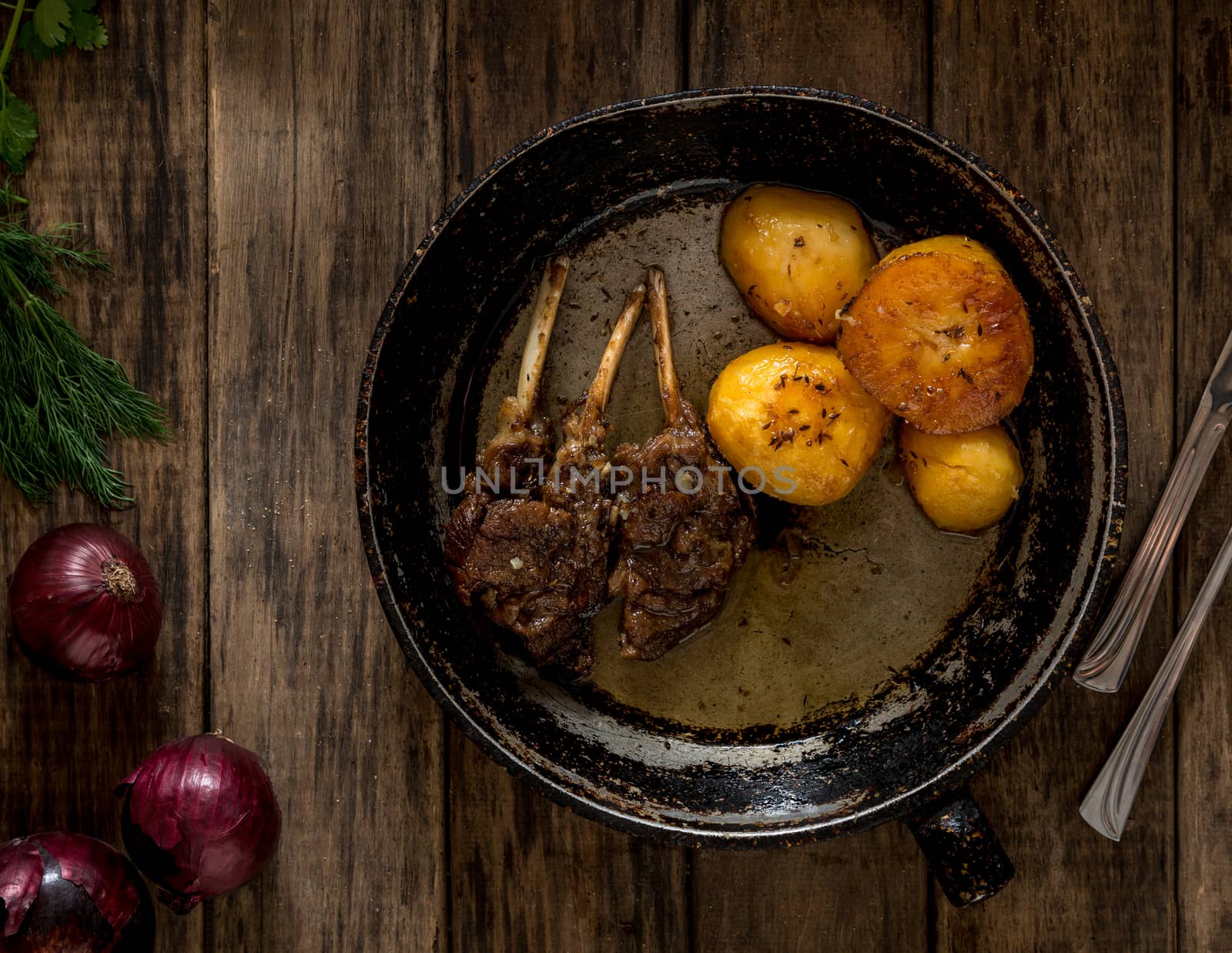 fried potatoes and meat in an old frying pan on wooden boards, top view