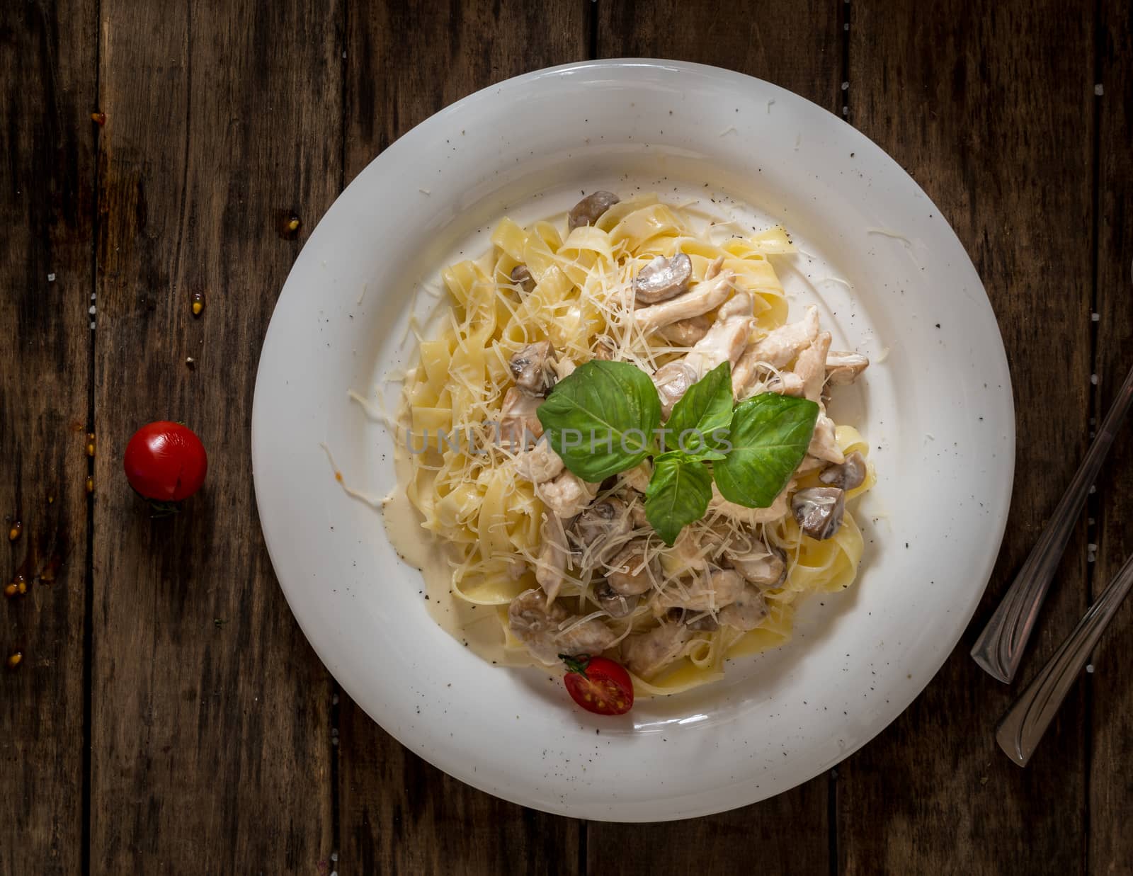 the dish of mushrooms and noodles decorated with a leaf of lettuce on wooden background, top view