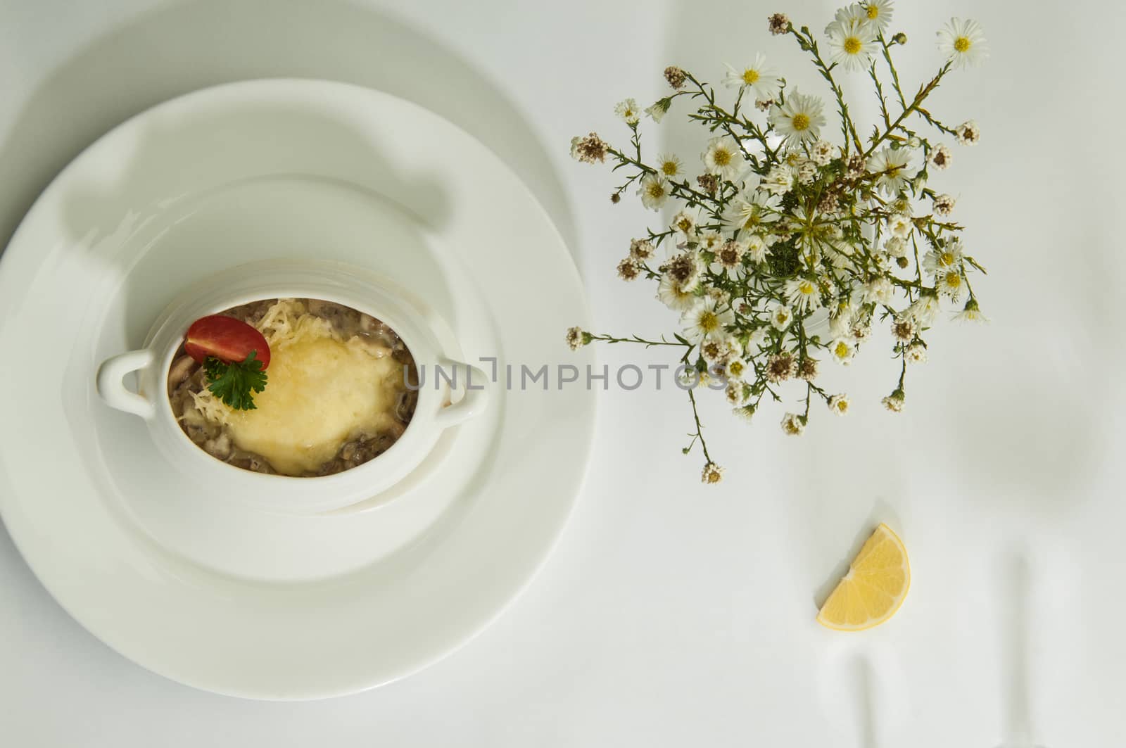 mushroom soup with lemon slices on a white surface with the shadow of wine glasses