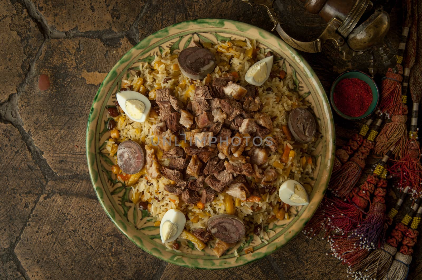 oriental dishes on decorative old tiles. pilaf and pitcher on decorative old paving stones