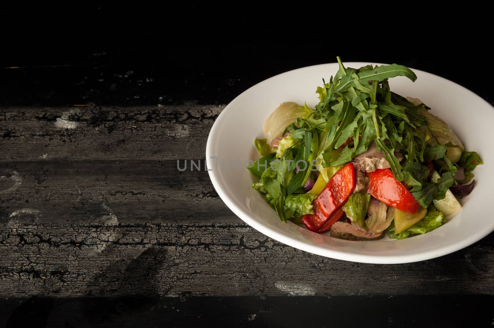 meat salad in a white plate on a wooden old surface