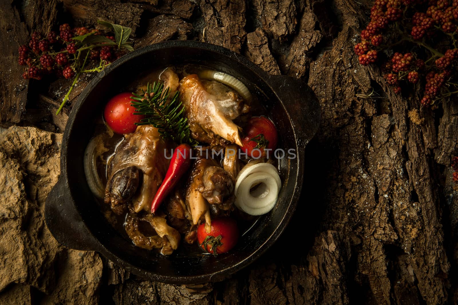 chicken dish with vegetables in a frying pan on the background of tree bark