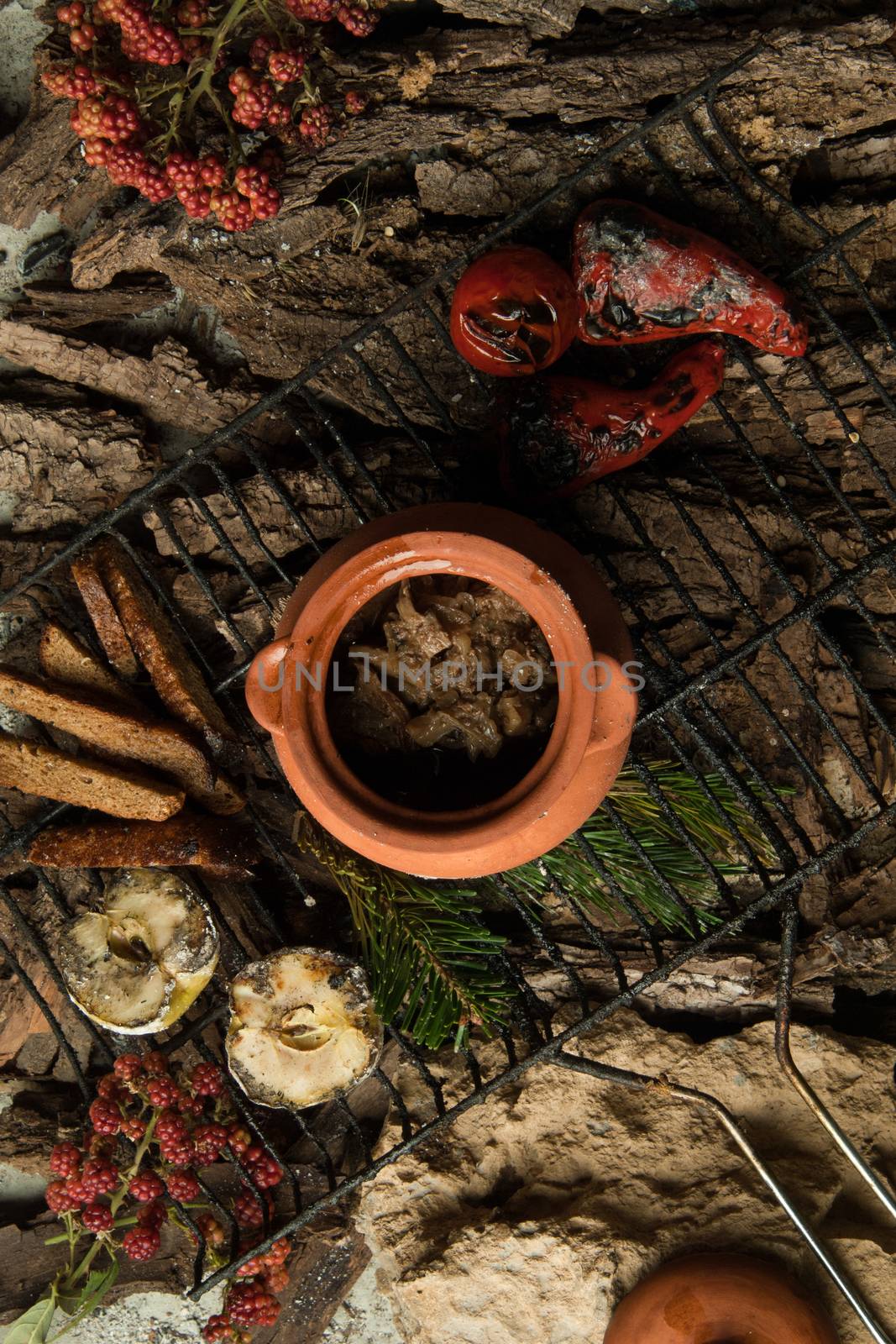 vegetarian dish in a clay pot with roasted vegetables on the grill on a background of tree bark