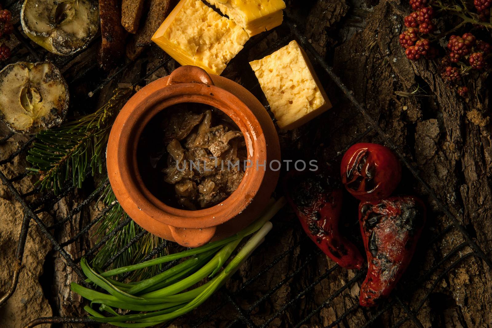 vegetarian dish in a clay pot with roasted vegetables on the grill on a background of tree bark