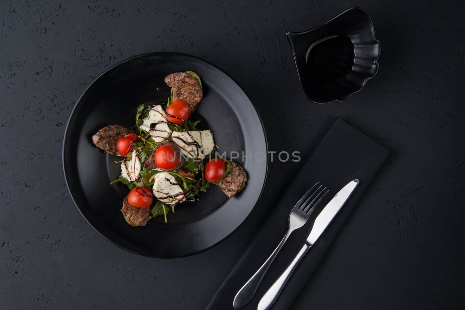 a dish of grilled meat on the black wooden surface, top view