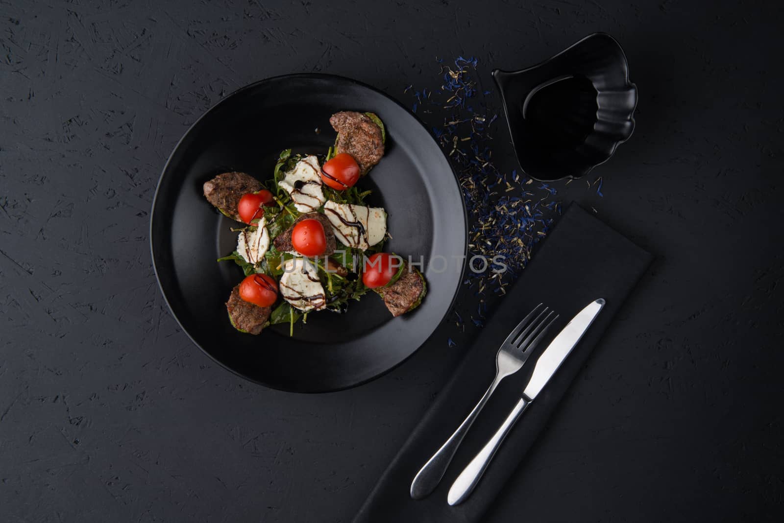 a dish of grilled meat on the black wooden surface, top view