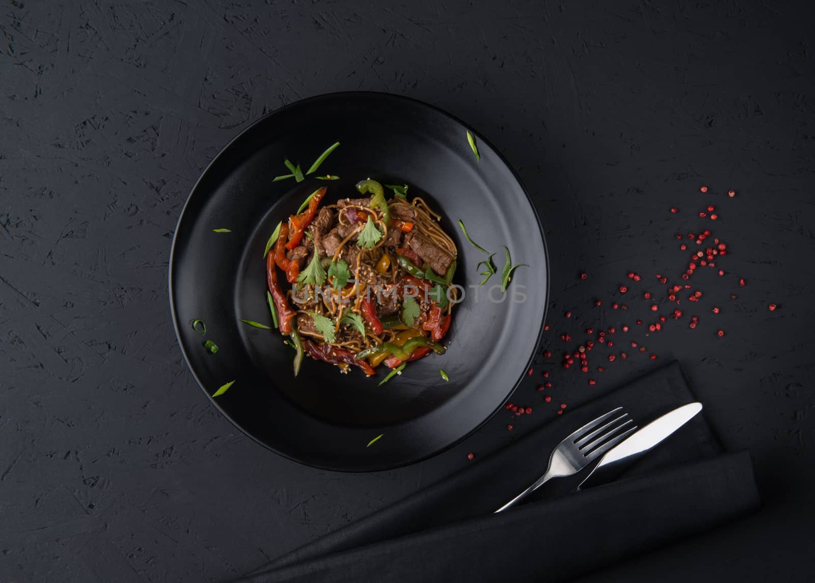 a dish of grilled meat on the black wooden surface, top view