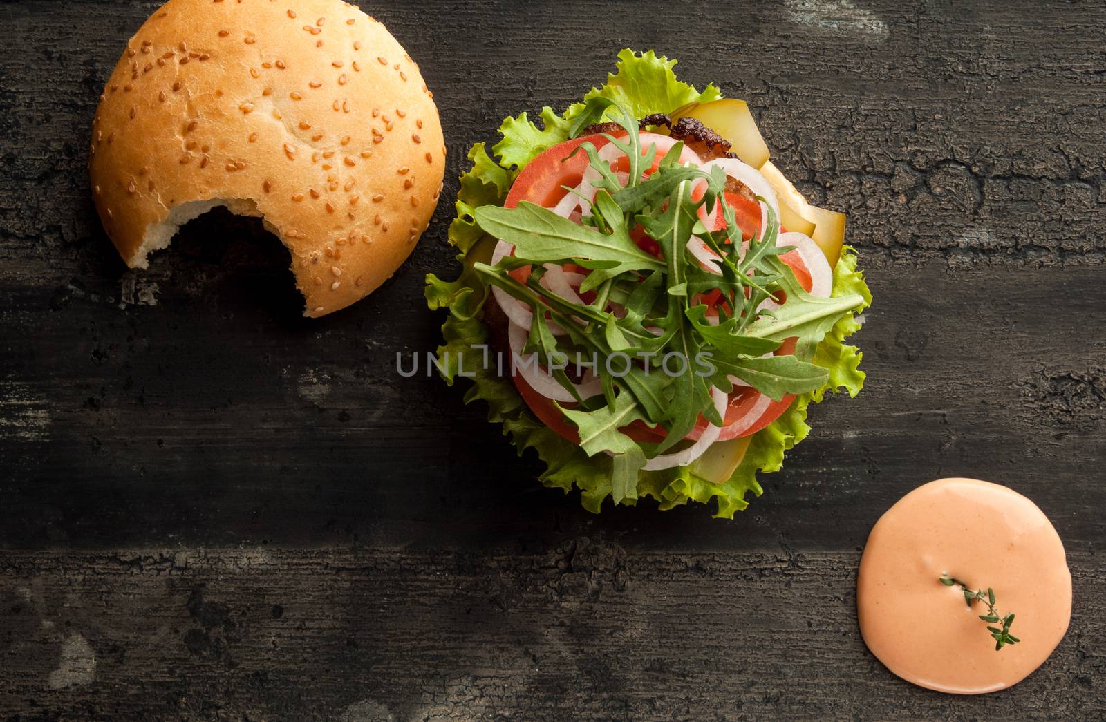 cheeseburger on an old wooden surface of dark color. hamburger with sauce and ketchup on an old wooden surface of dark color