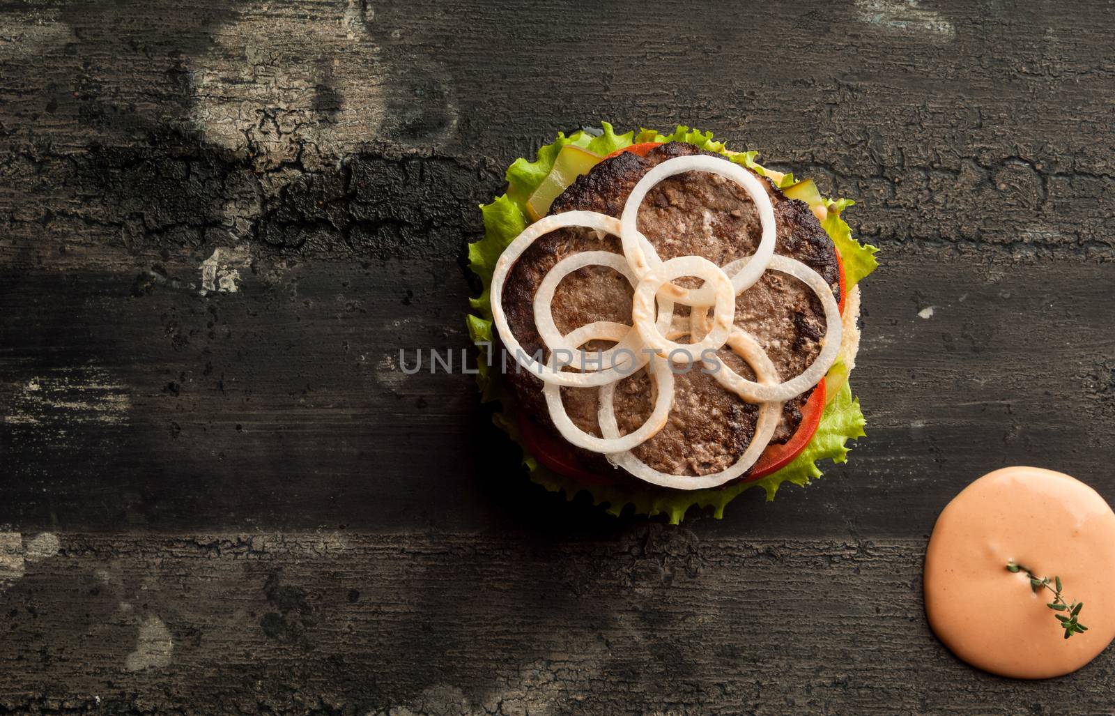 cheeseburger on an old wooden surface of dark color. hamburger with sauce and ketchup on an old wooden surface of dark color