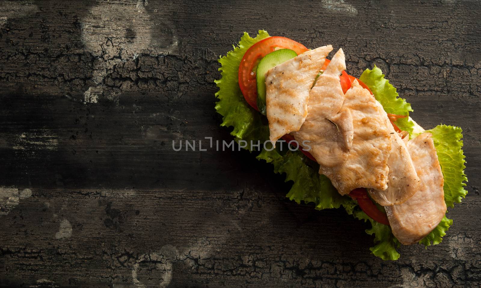 cheeseburger on an old wooden surface of dark color. hamburger with chicken meat on an old wooden surface of dark color