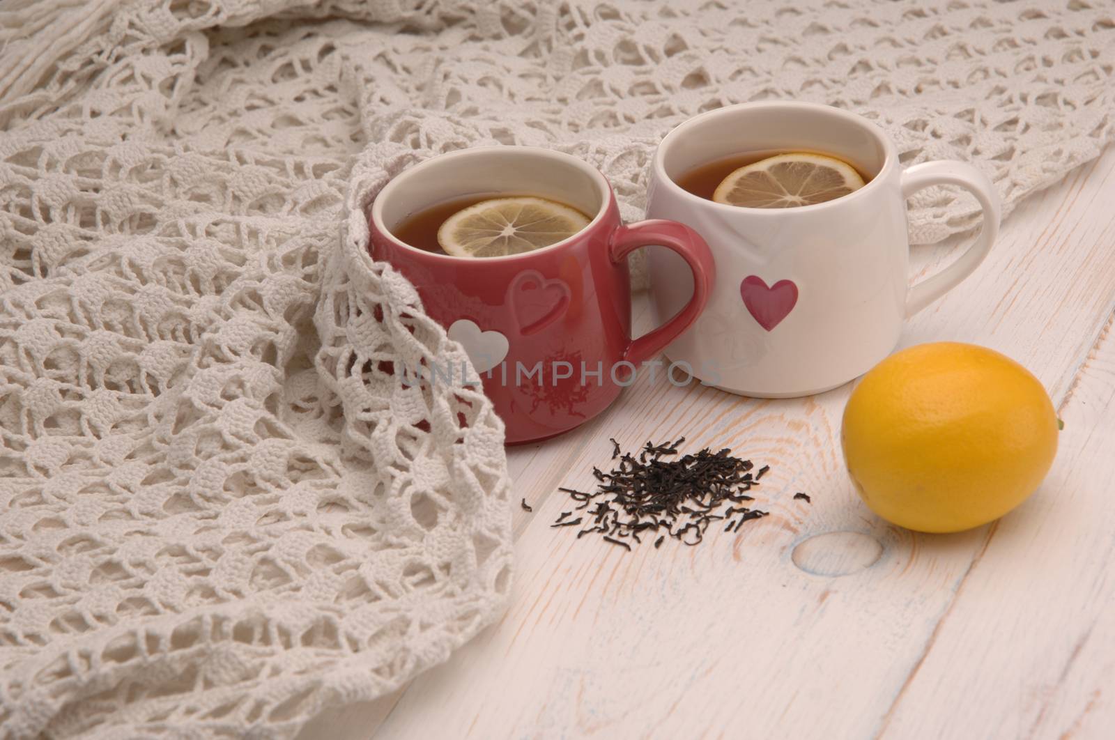 two cups of tea with lemon and scarf on wooden boards