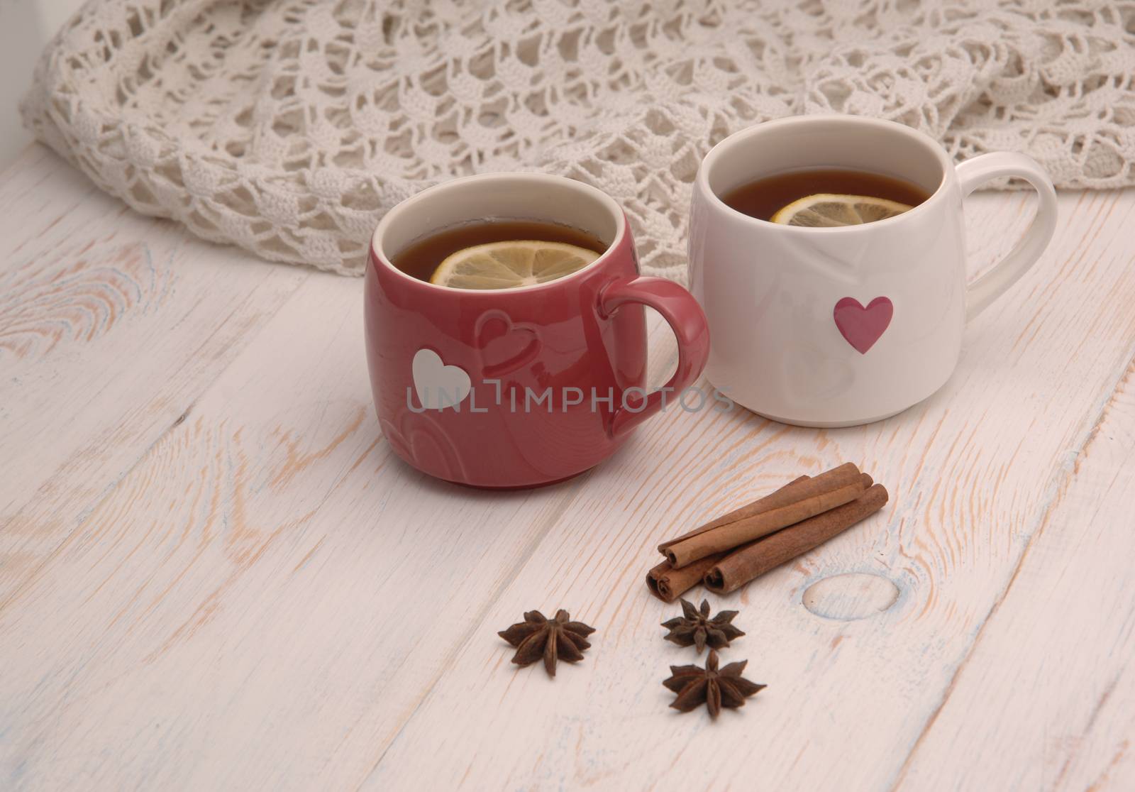 two cups of tea with lemon and scarf on wooden boards