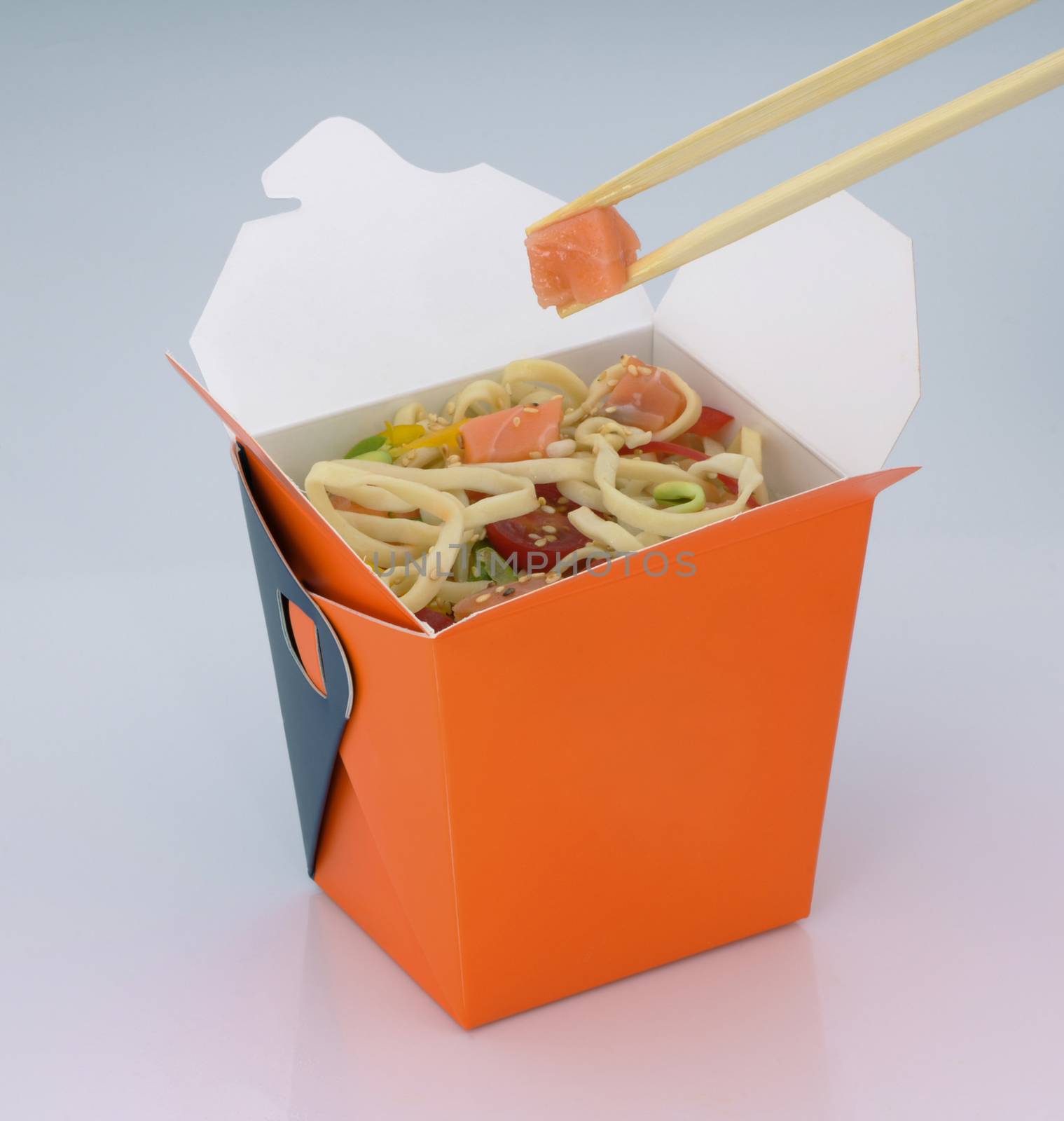 chinese food to takeaway. noodles with meat and vegetables in a cardboard box on a light background. takes chinese food with chopsticks
