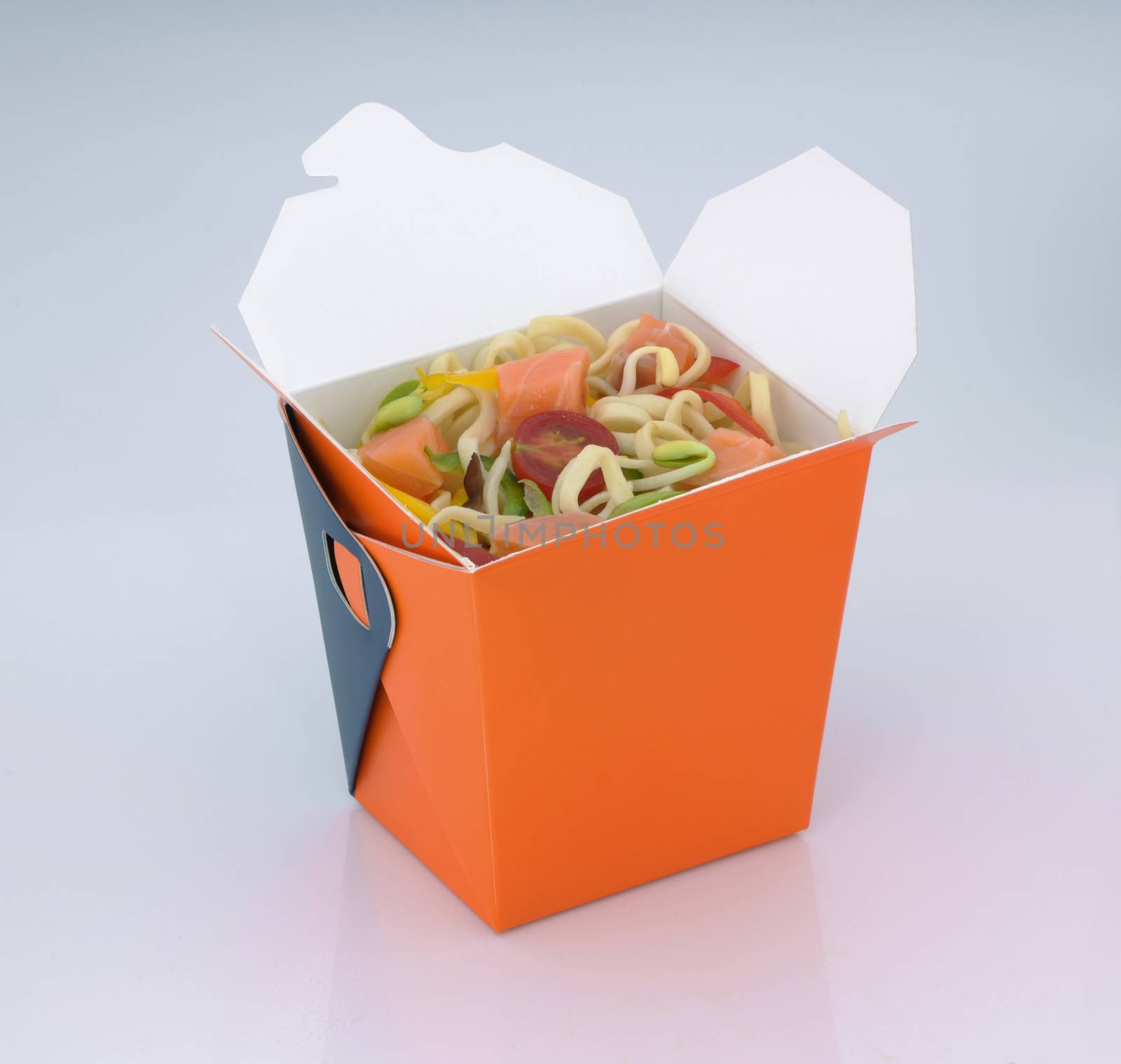 chinese food to takeaway. noodles with meat and vegetables in a cardboard box on a light background