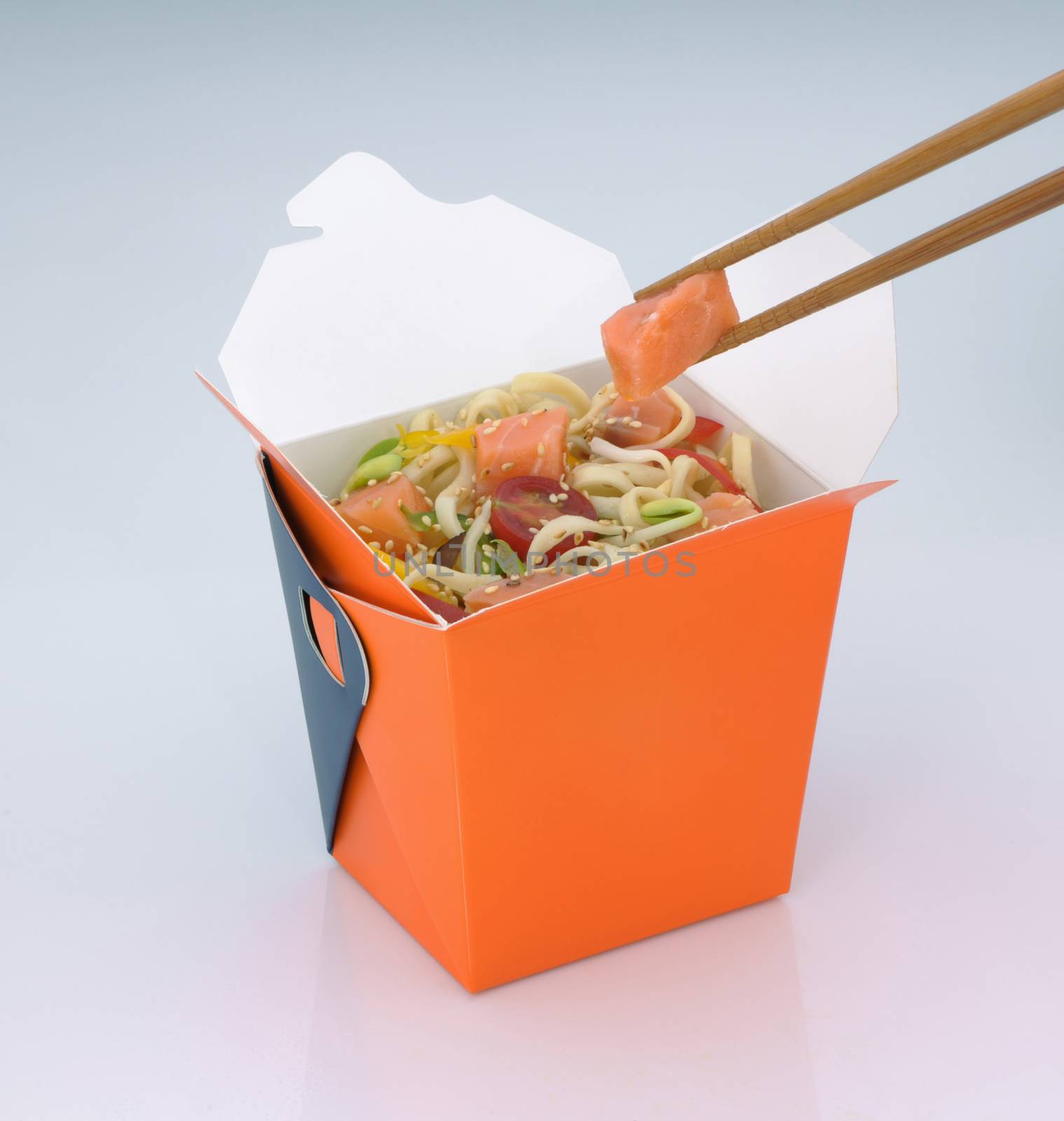 chinese food to takeaway. noodles with meat and vegetables in a cardboard box on a light background. takes chinese food with chopsticks