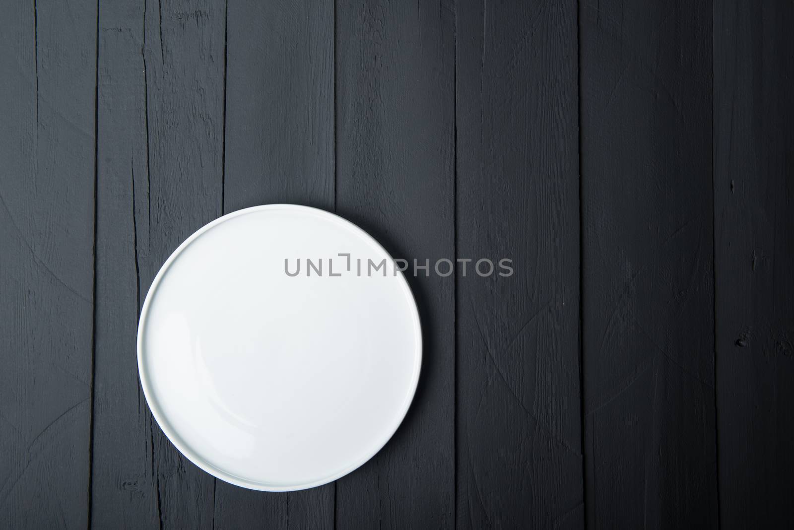 empty white plate on black wooden background