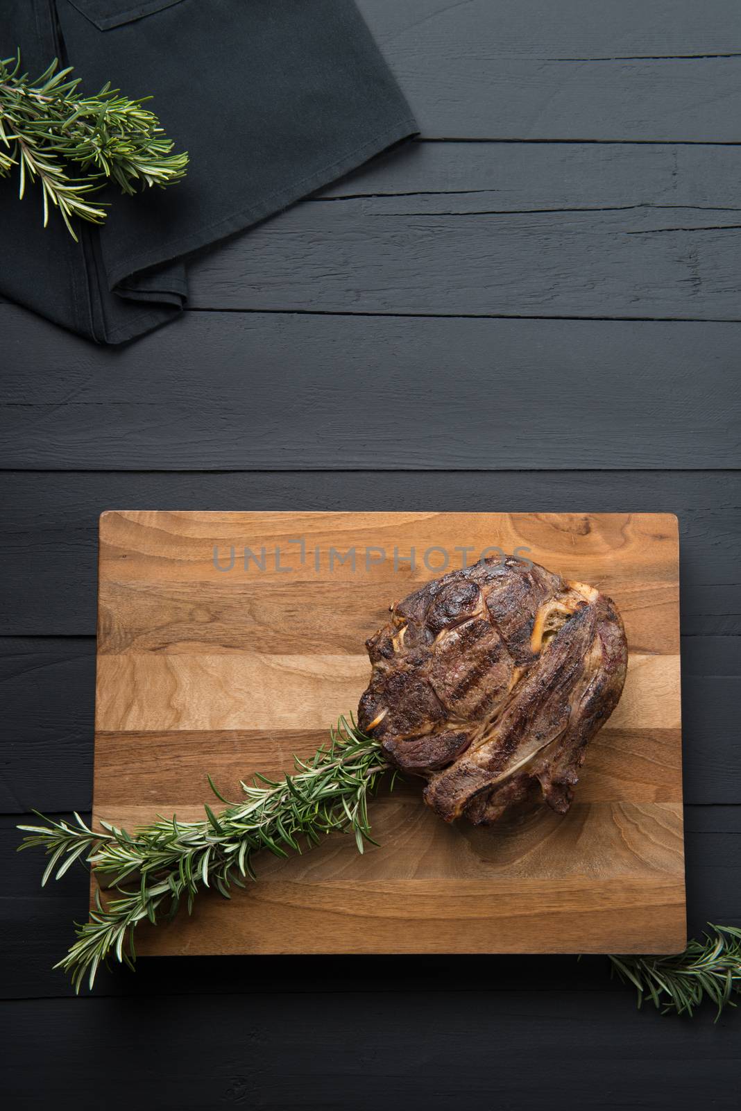 roasted meat with greens on a cutting board on a black wooden background