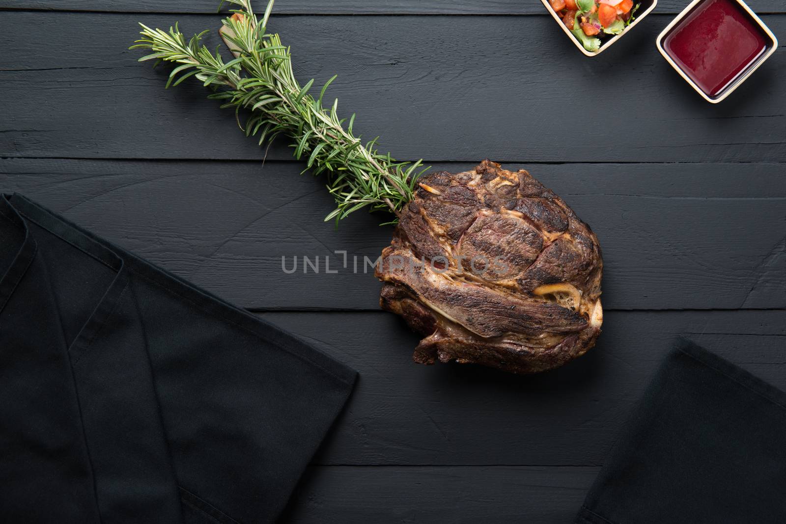 fried meat with greens, sauce and gravy on a black wooden background