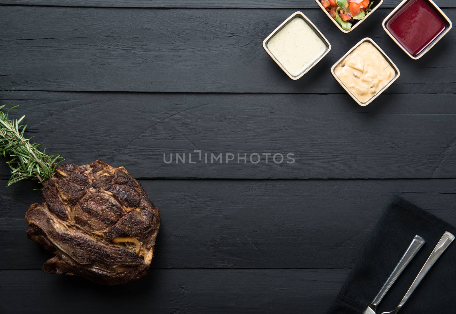 fried meat with greens, sauce and gravy on a black wooden background