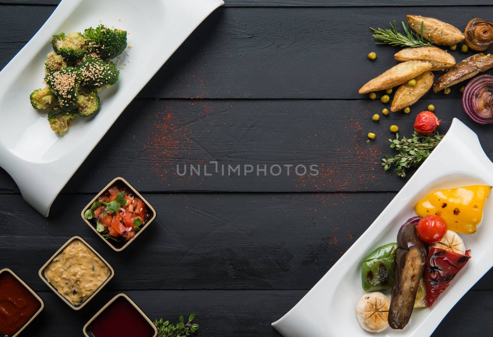 salads, vegetable food and gravy in plates on a black wooden background