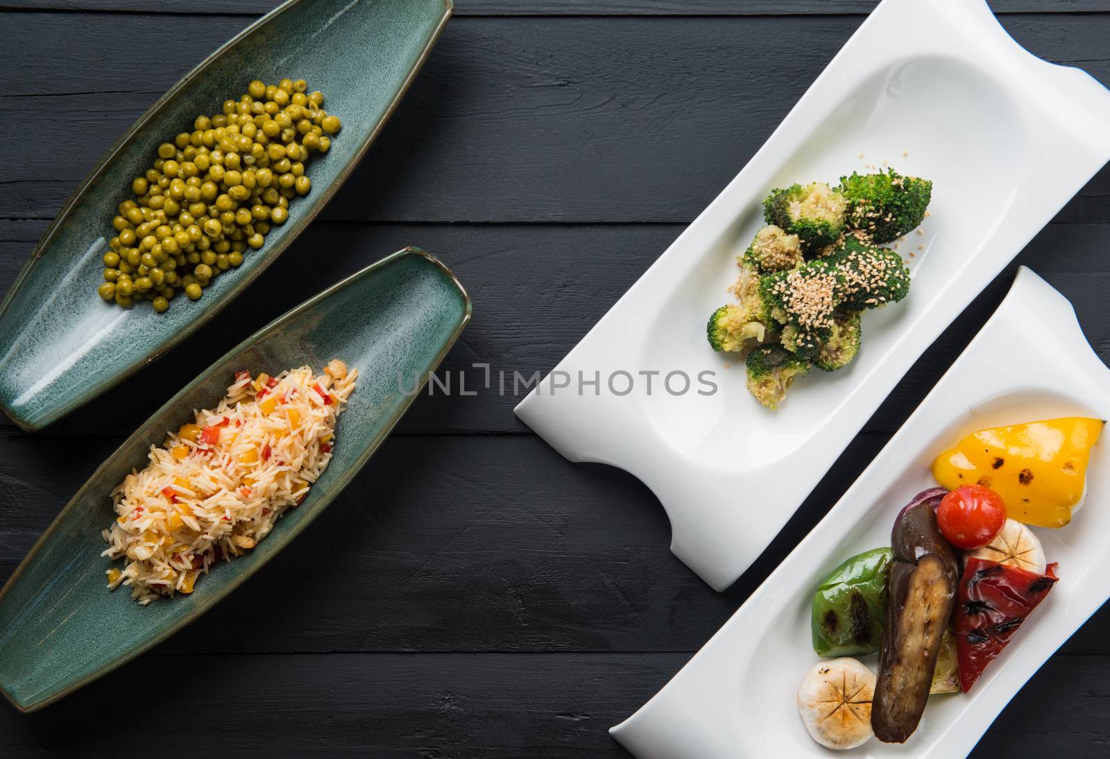 salads and vegetable food in plates on a black wooden background