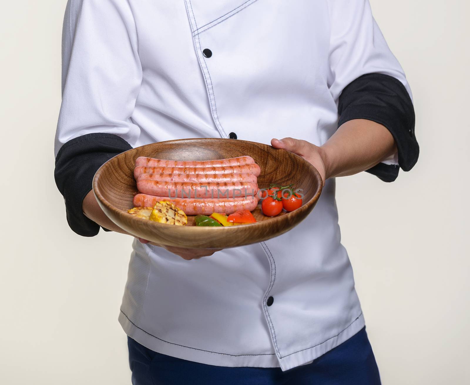 the cook holds a ready-made dish of fried sausages