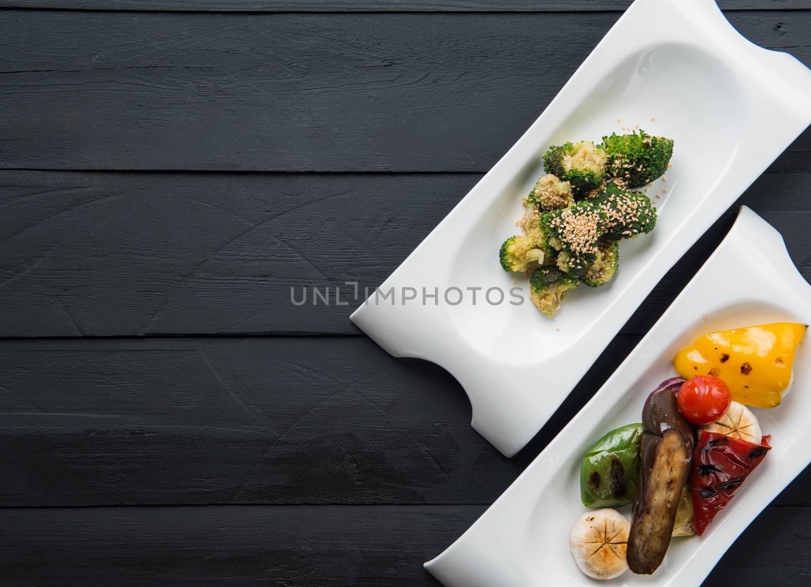 salads and vegetable food in plates on a black wooden background