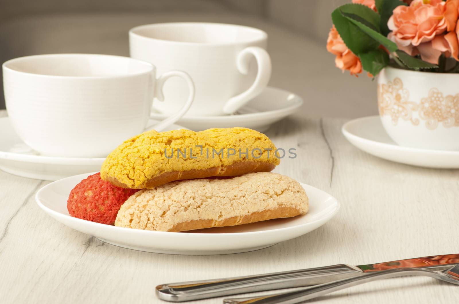 cake and two cups of coffee on a table with cutlery and flowers