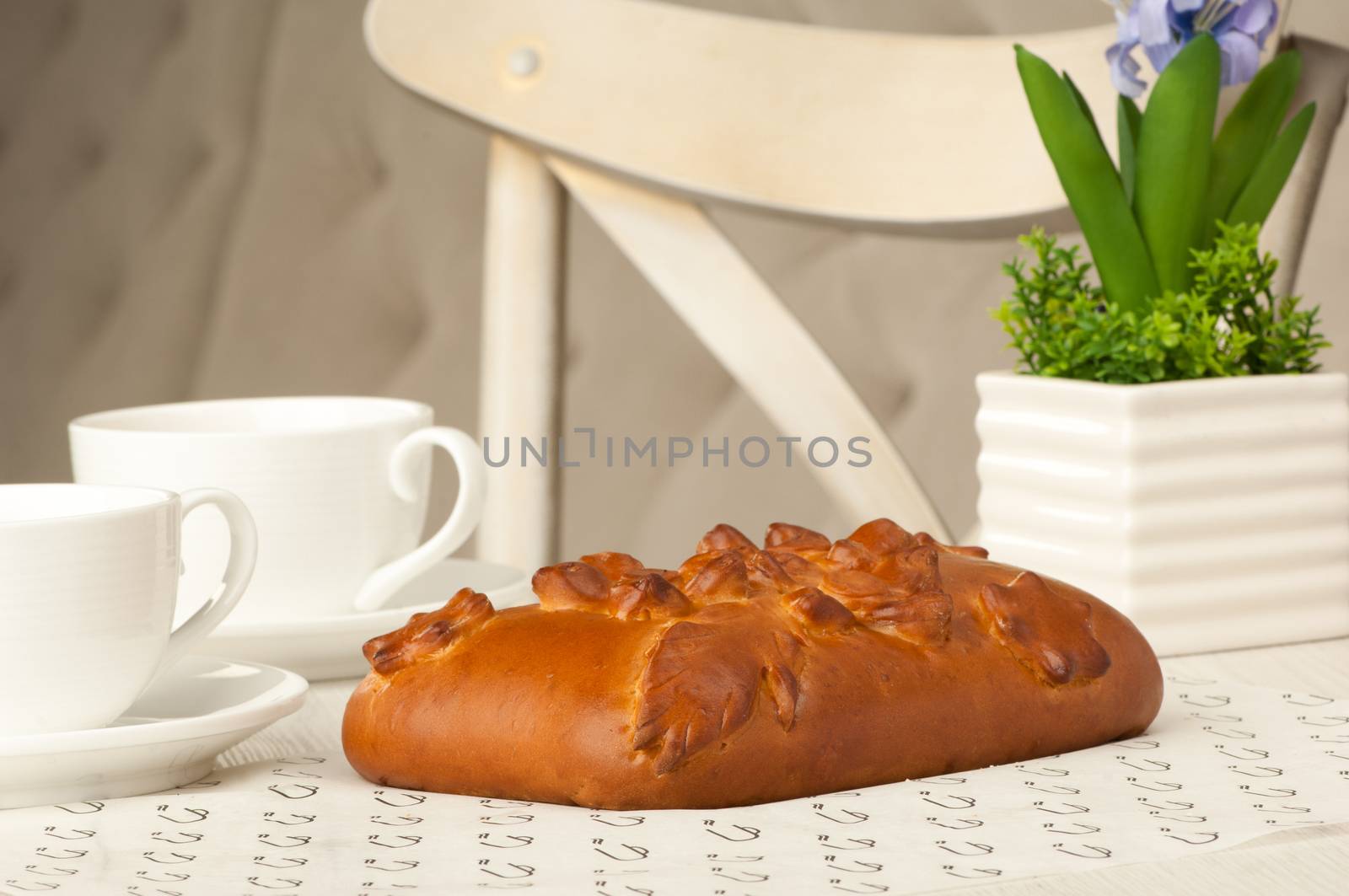 Pie and two cups of coffee on a table with flowers on the background of the chair