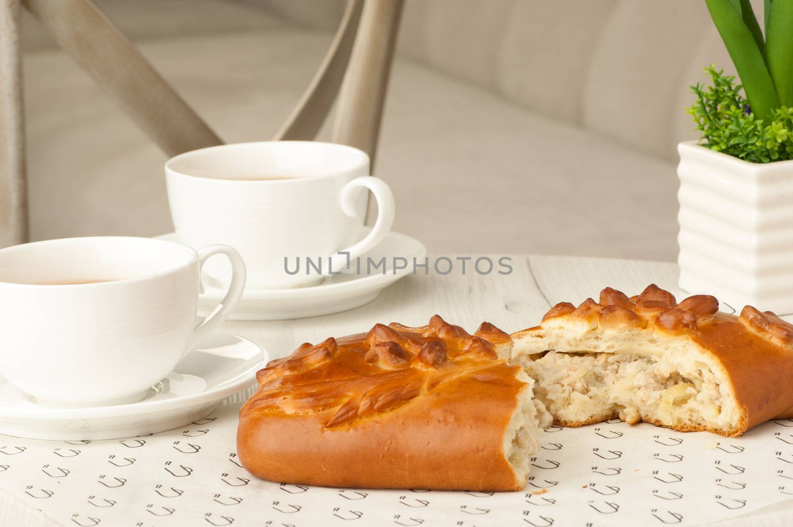 Pie and two cups of coffee on a table with flowers on the background of the chair