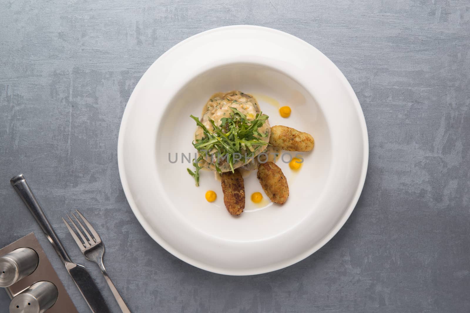 fried potatoes with greens in a plate on a gray background