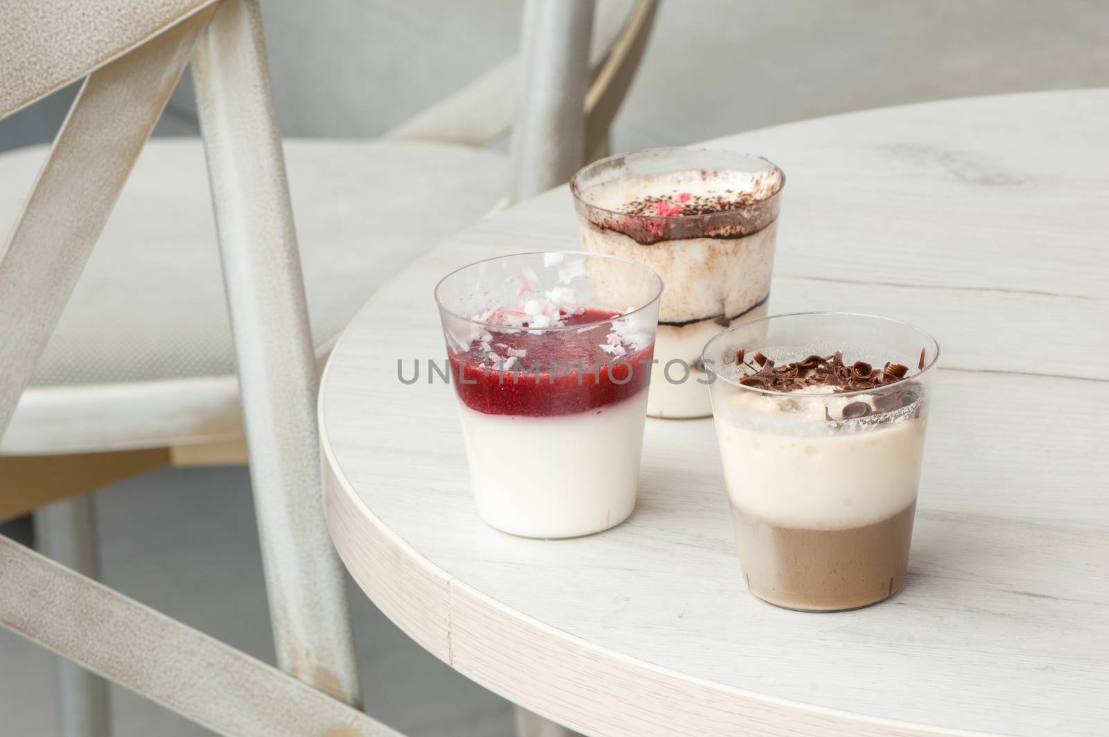 Three plastic glasses with a cocktail at the round table and chairs