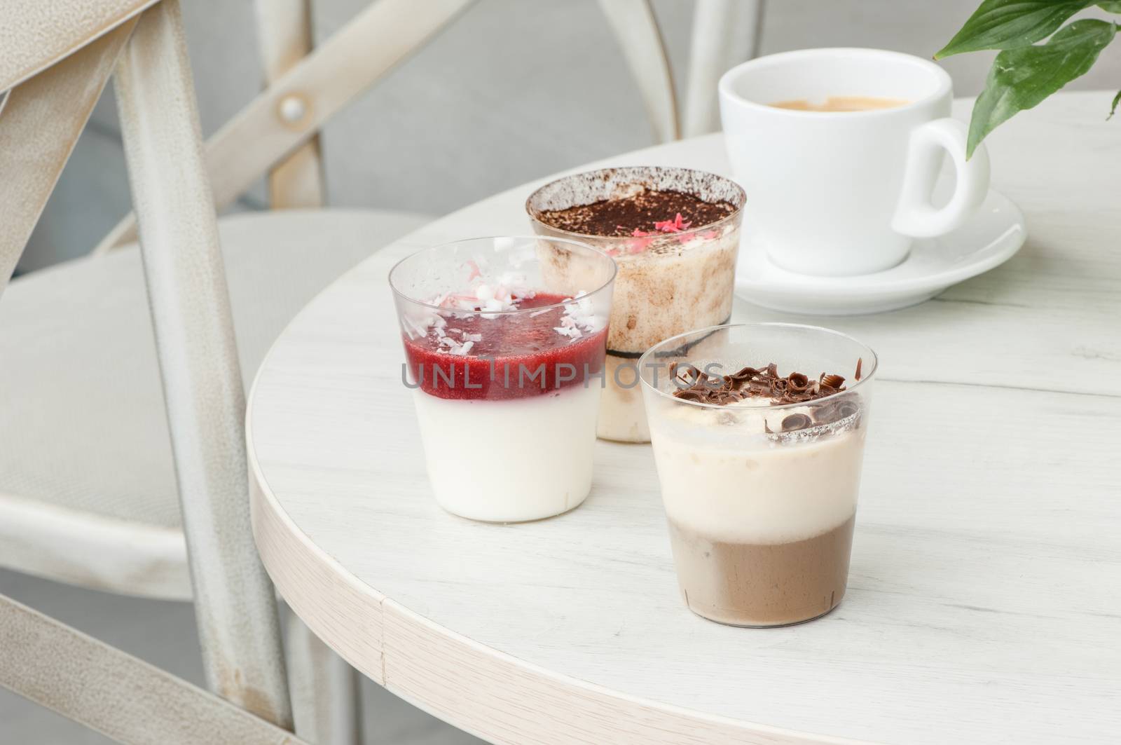 Three plastic glasses with a cocktail at the round table and a cup of coffee