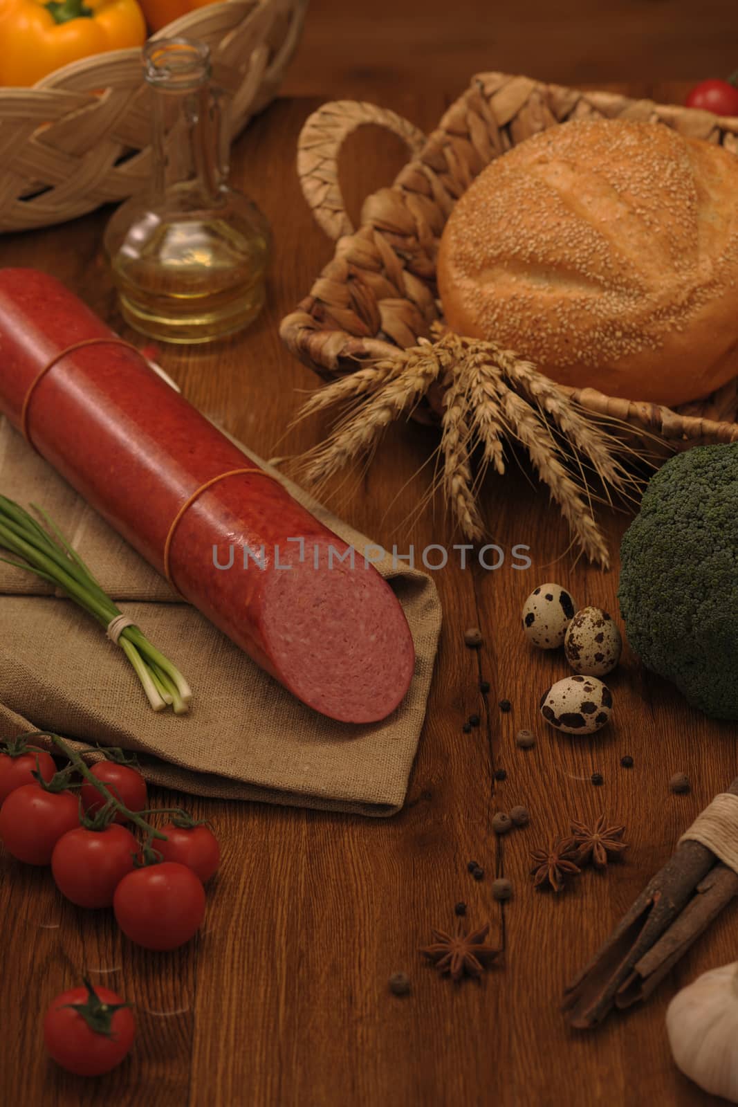 sausage and bread in a wicker basket and vegetables and garlic on a table
