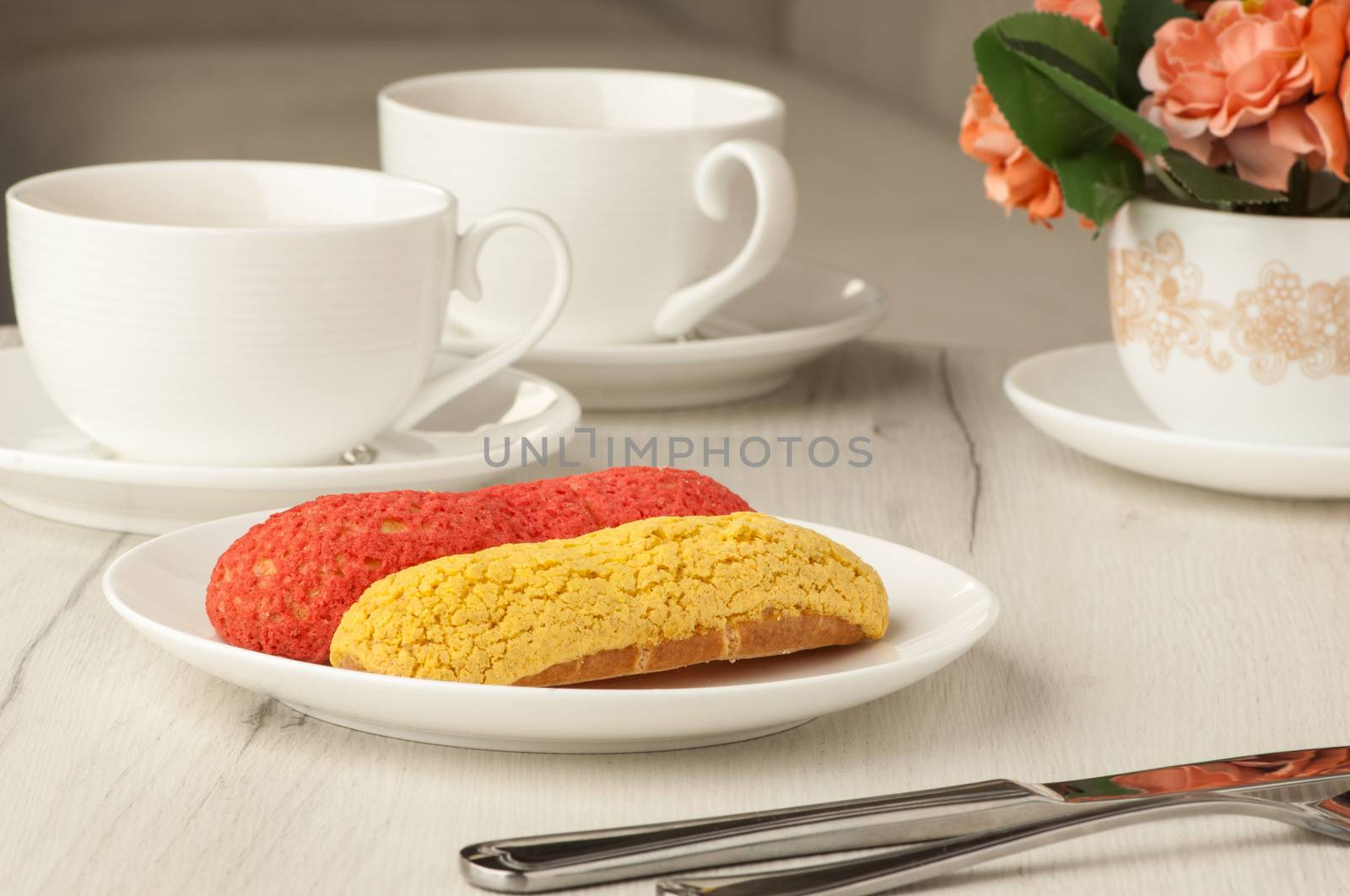 cake and two cups of coffee on a table with cutlery and flowers