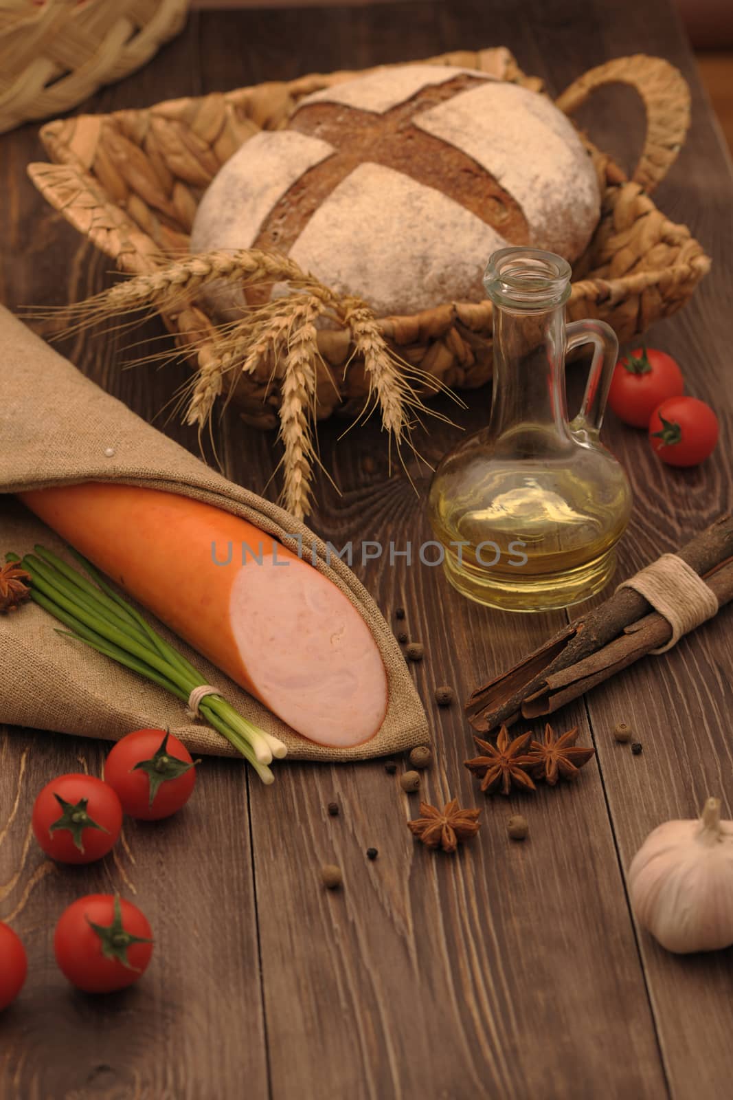 sausage and bread in a wicker basket and vegetables and garlic on a table