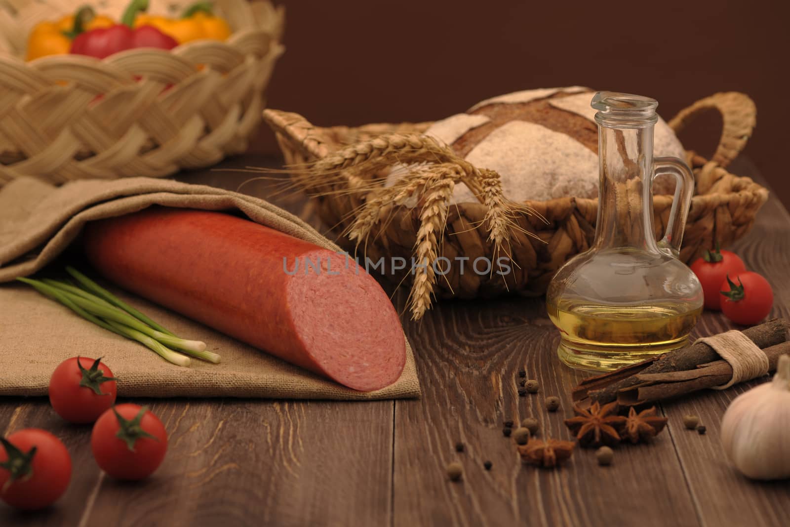 sausage and bread in a wicker basket and vegetables and garlic on a table