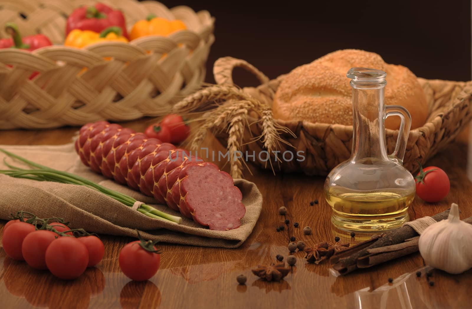 sausage and bread in a wicker basket and vegetables and garlic on a table