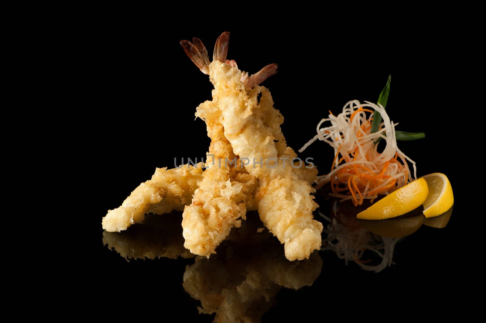 shrimp in tempura with lemon slices and salad on a black background with reflection