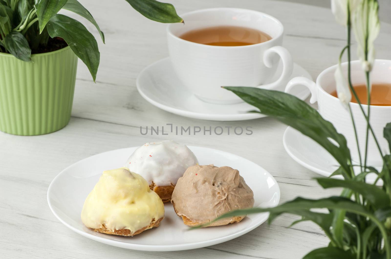 cake on a plate and two cups of tea on the table with flowers